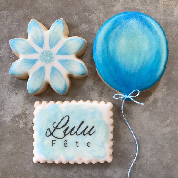 Decorated Lulu Fete cookies: a flower, a balloon, and a logo cookie